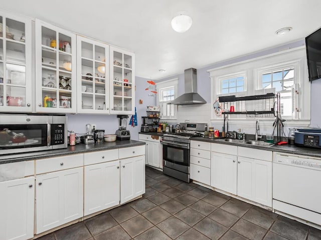 kitchen featuring sink, white cabinetry, dark tile patterned flooring, wall chimney range hood, and stainless steel appliances