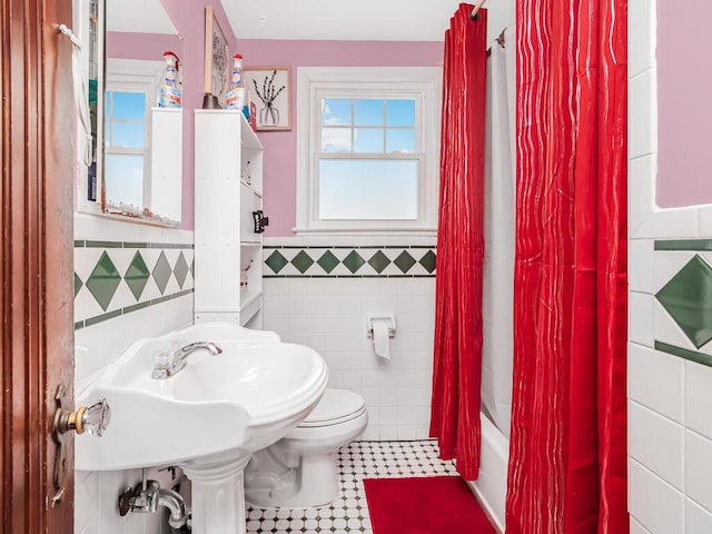 bathroom featuring toilet, shower / tub combo, and tile walls