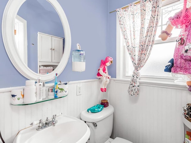 bathroom with sink, toilet, and wood walls