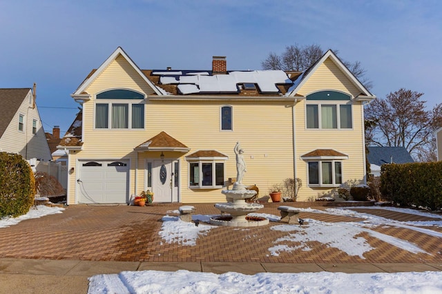 snow covered property with a garage