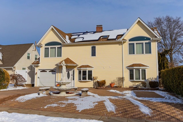 view of front facade featuring a garage and solar panels