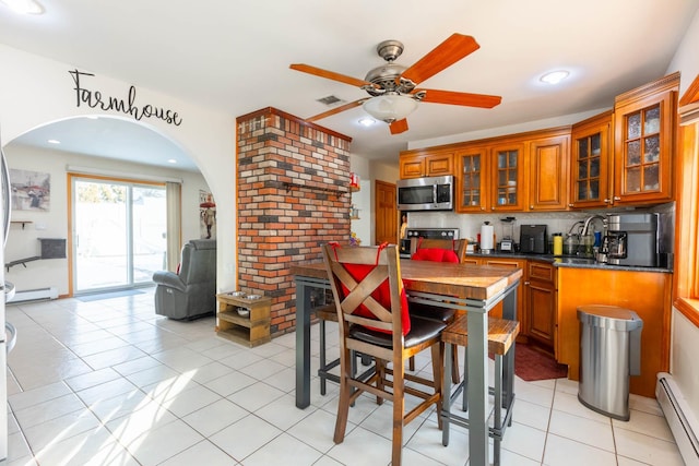 kitchen with ceiling fan, baseboard heating, range, and tasteful backsplash