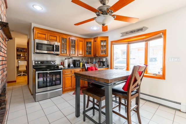 kitchen featuring appliances with stainless steel finishes, a baseboard heating unit, light tile patterned floors, decorative backsplash, and ceiling fan