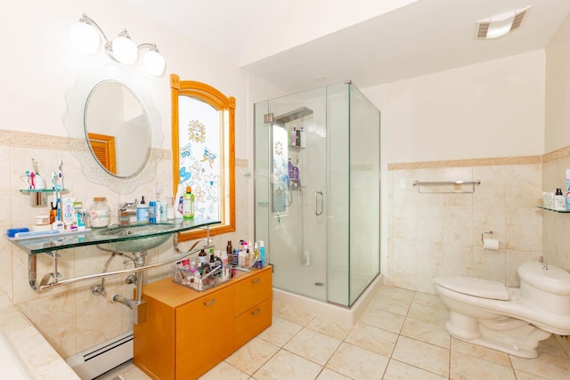 bathroom with a baseboard radiator, tile patterned floors, tile walls, toilet, and a shower with shower door