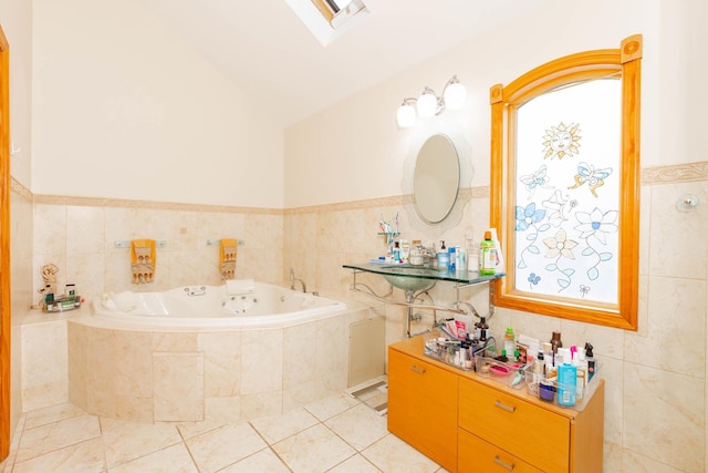 bathroom featuring vaulted ceiling with skylight, tile patterned floors, a relaxing tiled tub, and tile walls