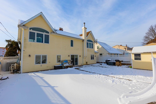 snow covered property with a storage shed and central AC