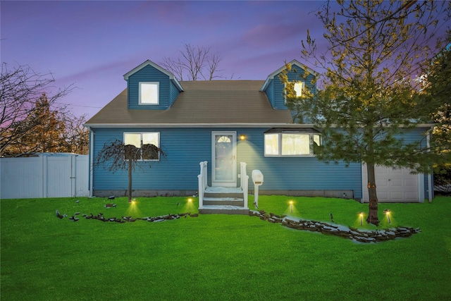 cape cod house featuring a garage and a yard