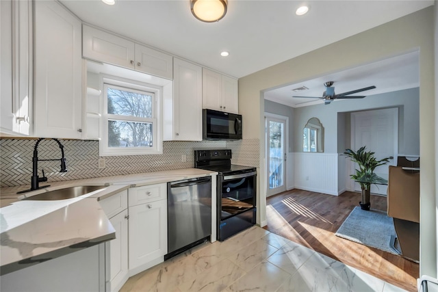 kitchen with ceiling fan, sink, backsplash, white cabinetry, and black appliances