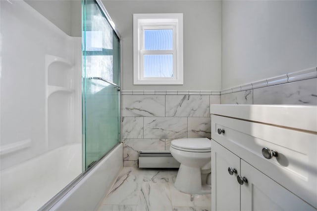 full bathroom with a baseboard radiator, tile walls, toilet, vanity, and bath / shower combo with glass door