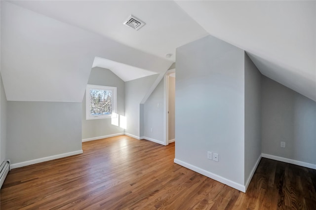 additional living space with hardwood / wood-style flooring, a baseboard radiator, and lofted ceiling