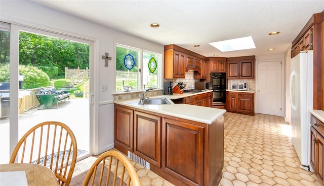 94 S Quaker Hill Rd, Pawling, NY 12564 - kitchen with appliances with stainless steel finishes, a skylight, light countertops, decorative backsplash, and a peninsula