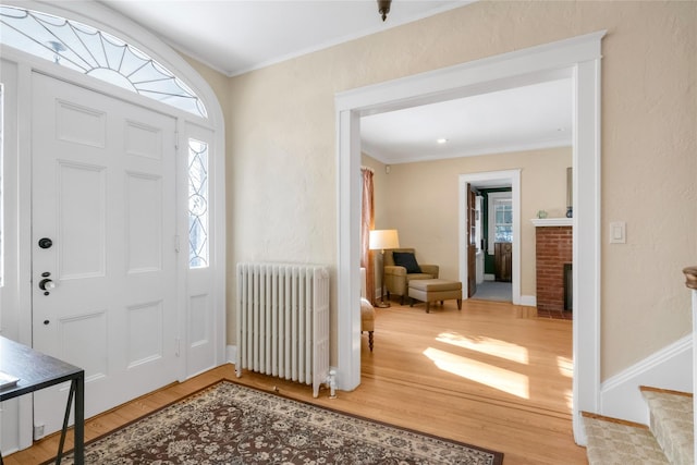 foyer entrance with radiator, ornamental molding, and hardwood / wood-style floors