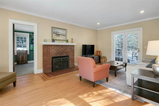 living room with a brick fireplace, ornamental molding, and light wood-type flooring