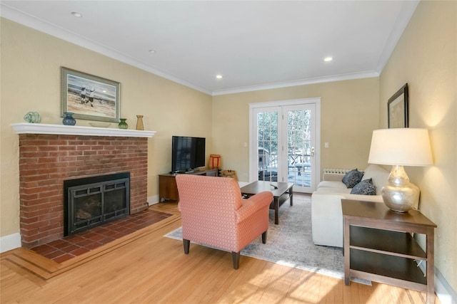 living room with a brick fireplace, hardwood / wood-style flooring, ornamental molding, and french doors