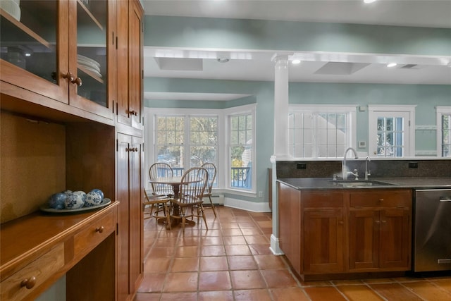 kitchen featuring sink, light tile patterned floors, stainless steel dishwasher, decorative columns, and decorative backsplash