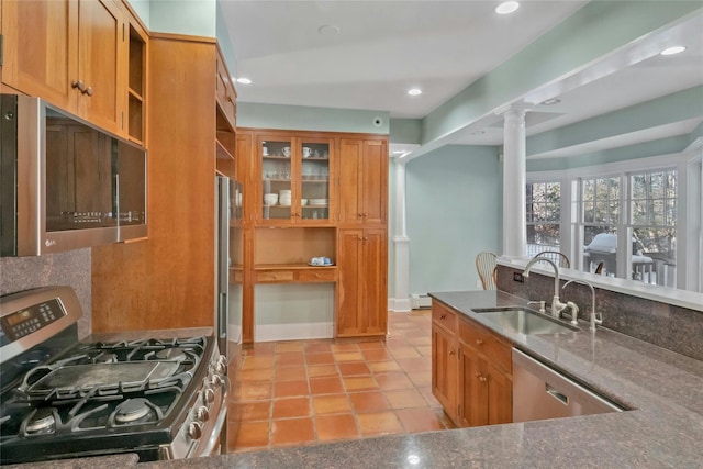 kitchen with light tile patterned flooring, decorative columns, a baseboard radiator, sink, and stainless steel appliances