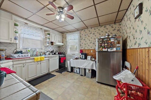 kitchen with white cabinetry, tile countertops, stainless steel refrigerator, white dishwasher, and a drop ceiling