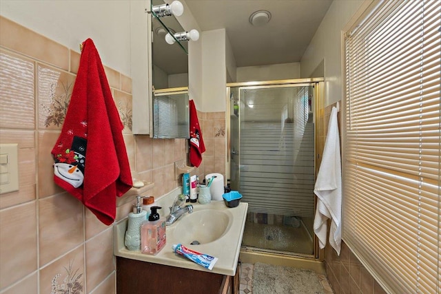 bathroom with vanity, tile walls, and a shower with shower door