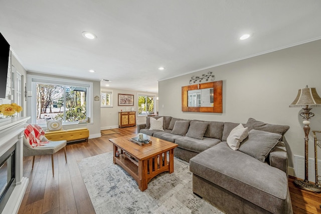 living room with a healthy amount of sunlight, ornamental molding, and light wood-type flooring