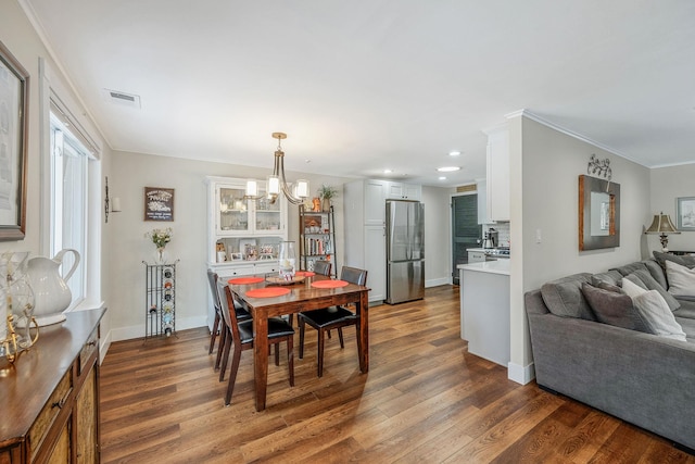 dining area with crown molding, a notable chandelier, and dark hardwood / wood-style flooring