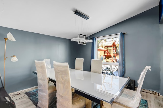 dining space featuring vaulted ceiling, a notable chandelier, and light wood-type flooring