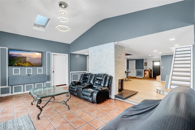 living room with lofted ceiling with skylight and light tile patterned floors