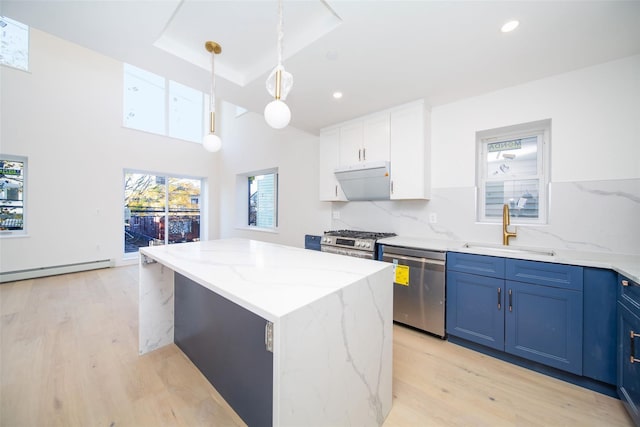 kitchen with a kitchen island, white cabinetry, stainless steel appliances, sink, and hanging light fixtures