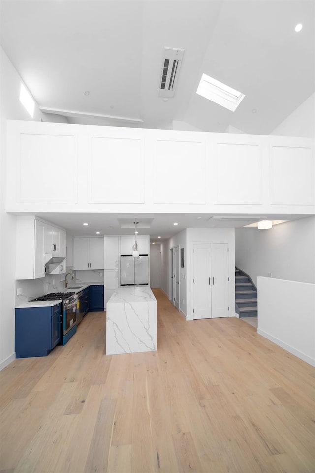 interior space with sink, light wood-type flooring, and vaulted ceiling with skylight