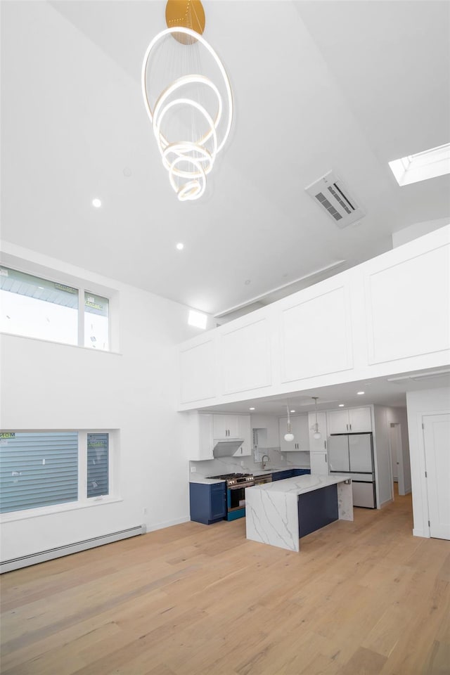 kitchen with white cabinets, a kitchen island, decorative light fixtures, blue cabinetry, and refrigerator