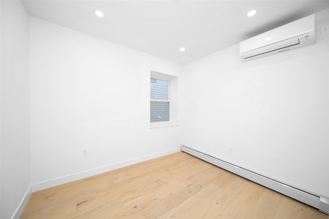 spare room featuring an AC wall unit, baseboard heating, and hardwood / wood-style flooring