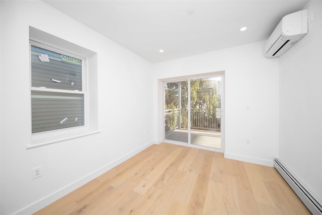 empty room with a wall mounted air conditioner, light hardwood / wood-style flooring, and a baseboard heating unit