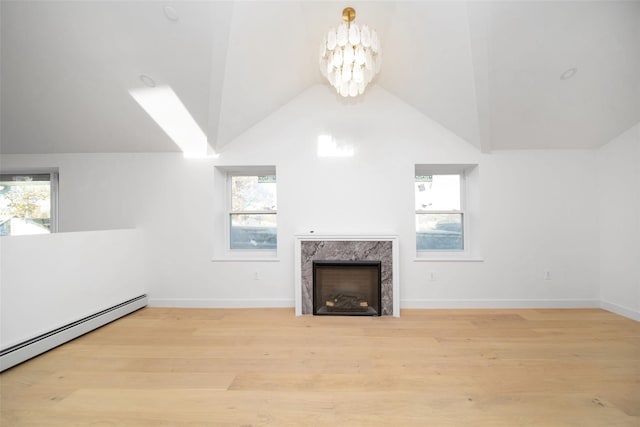 unfurnished living room featuring a high end fireplace, a baseboard heating unit, light hardwood / wood-style flooring, an inviting chandelier, and lofted ceiling