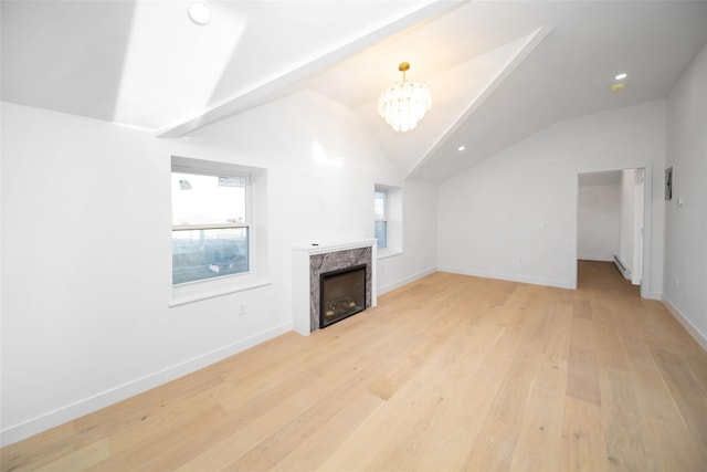 unfurnished living room with light hardwood / wood-style flooring, lofted ceiling, a notable chandelier, and a fireplace