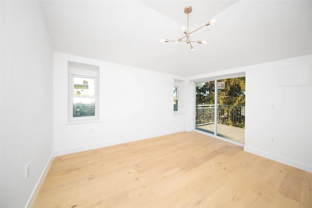 spare room with light wood-type flooring and a notable chandelier