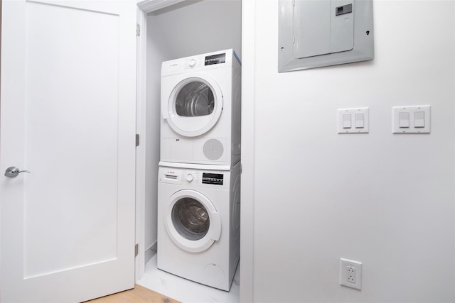 laundry room featuring electric panel and stacked washer and dryer