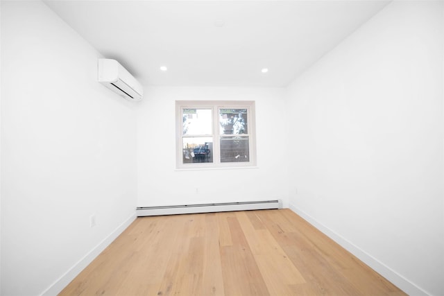 unfurnished room with a baseboard heating unit, light hardwood / wood-style floors, and a wall unit AC