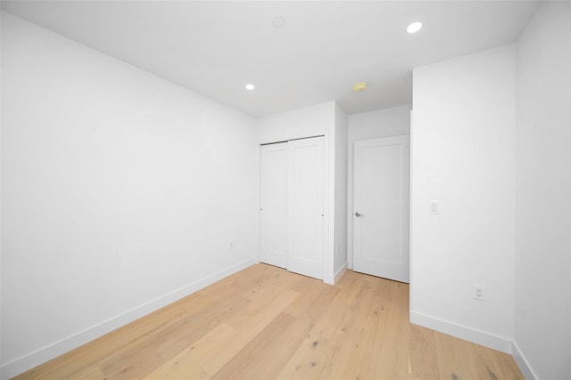 unfurnished bedroom with a closet and light wood-type flooring