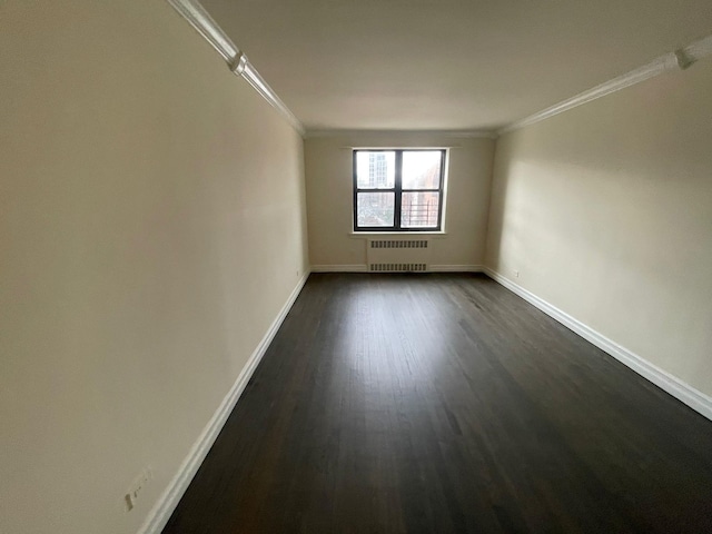 spare room featuring crown molding, dark hardwood / wood-style floors, and radiator