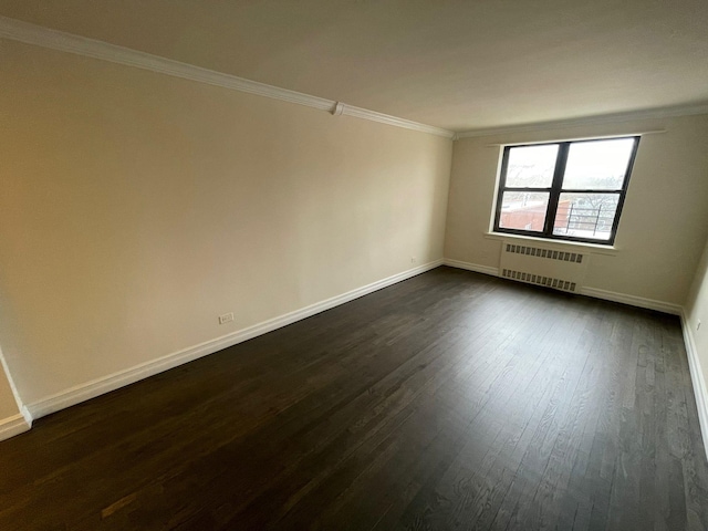 spare room with dark hardwood / wood-style floors, radiator heating unit, and crown molding