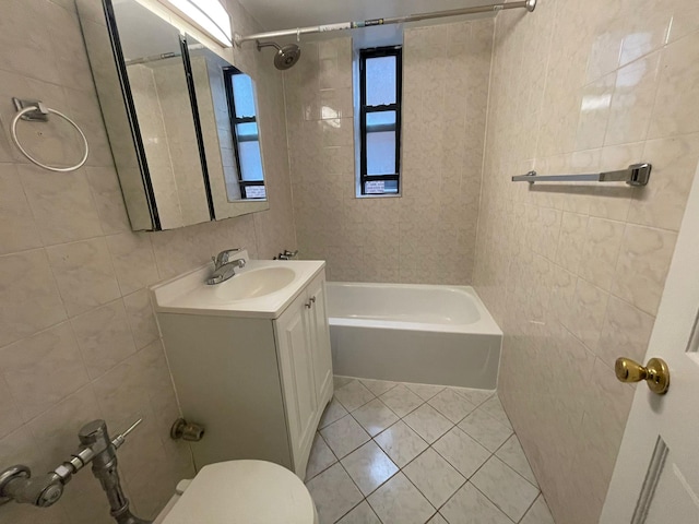 full bathroom with tile patterned flooring, tile walls, tiled shower / bath combo, toilet, and vanity