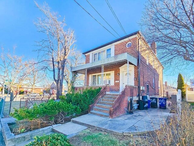 196-64 45th Ave, Flushing, NY 11358 - view of front of home with brick siding, fence, a garden, and stairs