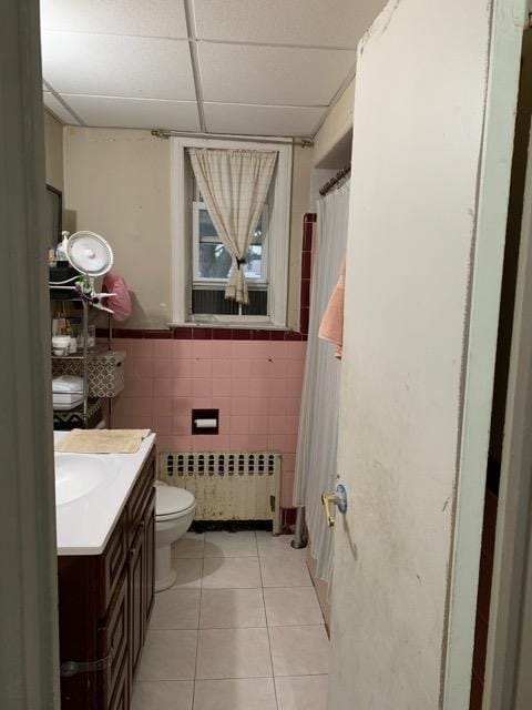 196-64 45th Ave, Flushing, NY 11358 - bathroom with radiator heating unit, a paneled ceiling, tile patterned floors, tile walls, and vanity