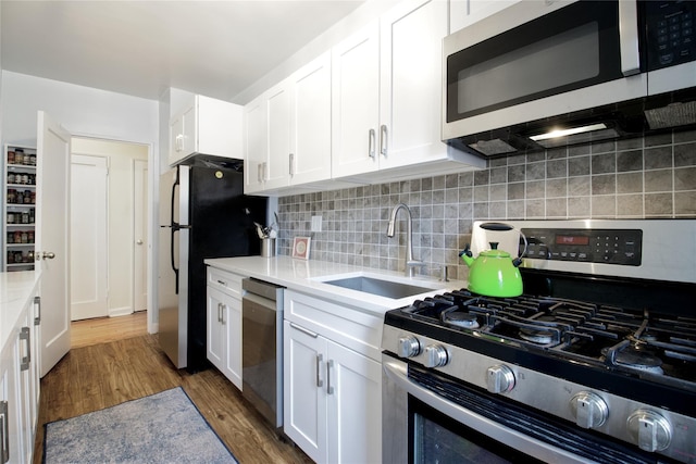 kitchen with white cabinets, dark wood-type flooring, stainless steel appliances, decorative backsplash, and sink