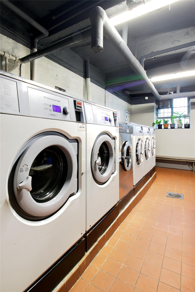 laundry area with a baseboard radiator, washer and clothes dryer, and light tile patterned flooring