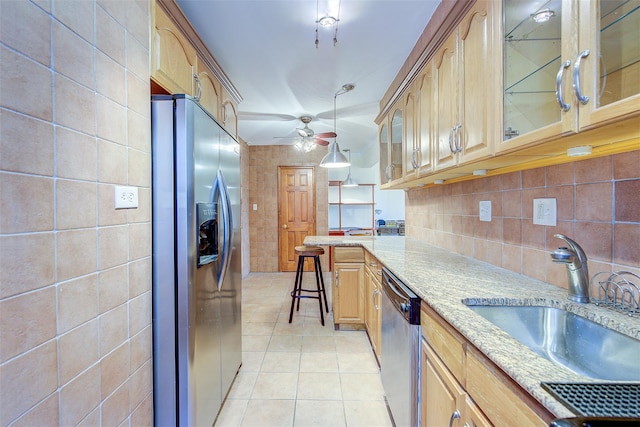 kitchen featuring light tile patterned floors, appliances with stainless steel finishes, glass insert cabinets, a sink, and light stone countertops