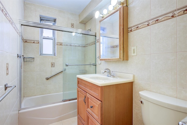 bathroom with toilet, shower / bath combination with glass door, tile walls, and vanity