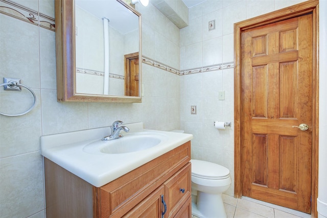 half bath featuring toilet, vanity, tile walls, and tile patterned floors