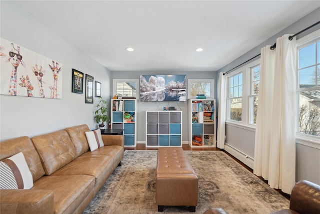 living room featuring a healthy amount of sunlight, wood-type flooring, and a baseboard heating unit