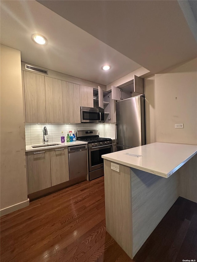 kitchen featuring appliances with stainless steel finishes, decorative backsplash, sink, dark hardwood / wood-style floors, and kitchen peninsula