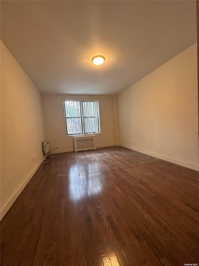 unfurnished room with dark wood-type flooring and radiator